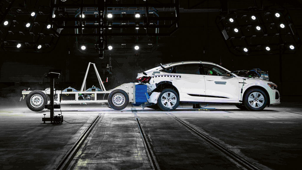 En rörlig murbräcka som färdas i 80 kilometer i timmen rammar bakänden på en vit Audi Q8 e-tron och knuffar den flera meter framåt. 