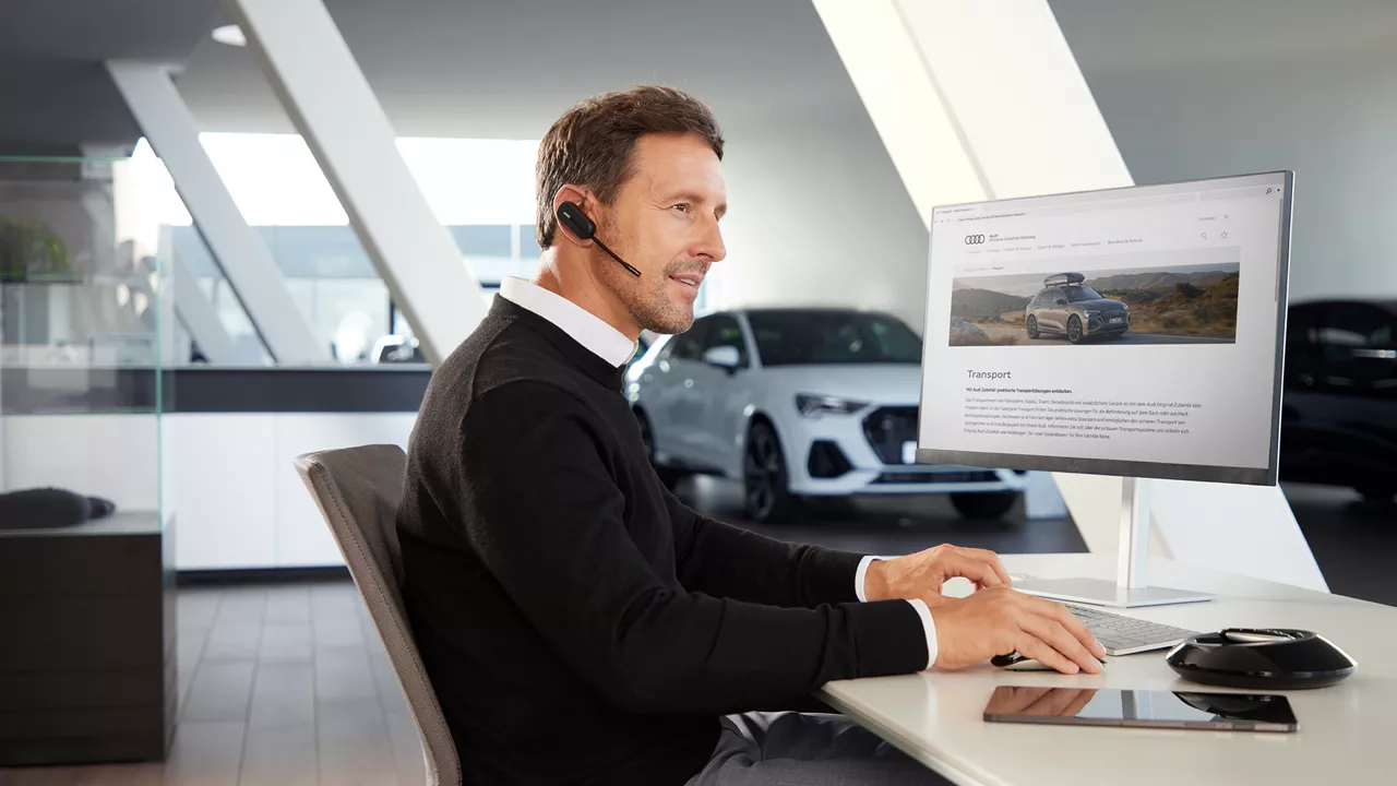 Ein Mann sitzt mit Headset an einem Computer