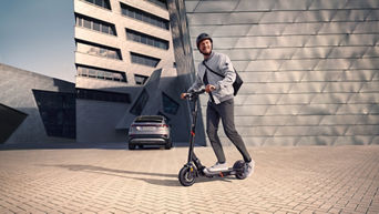 Mann mit Helm steht neben einem E-Scooter von Audi