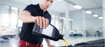 An Audi mechanic pouring Audi brand oil into the engine of an Audi vehicle