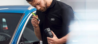 An Audi mechanic inspecting a part from an Audi vehicle with a torch