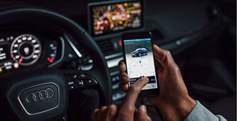 A driver in an Audi vehicle using the myAudi app displayed on their mobile phone