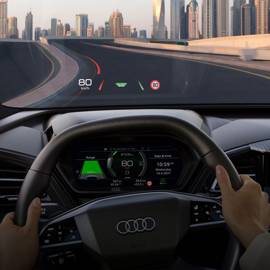 Driver's perspective inside an Audi car with hands on steering wheel and digital dashboard display