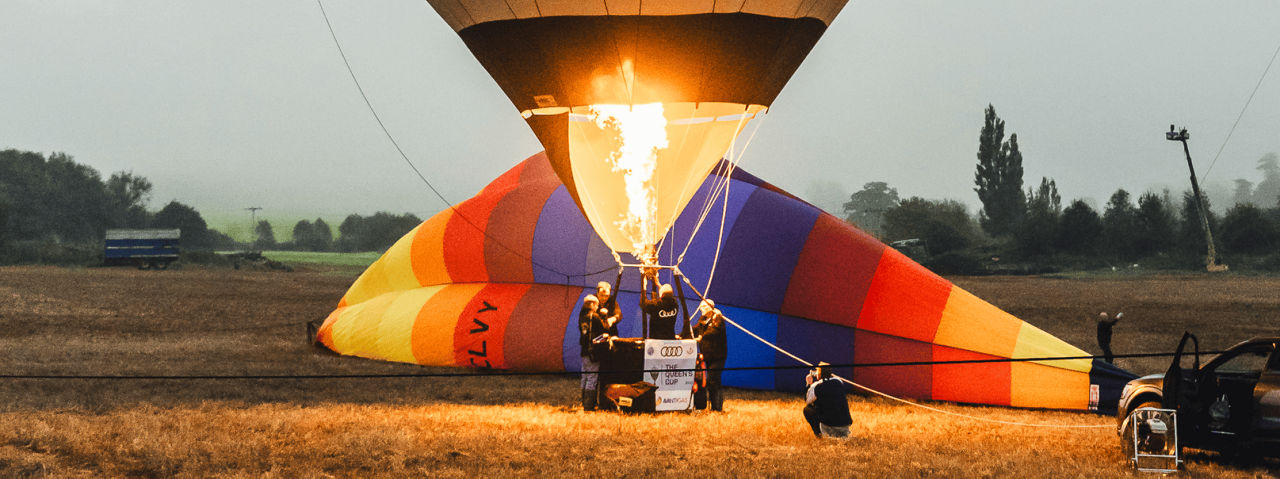 A colourful hot air balloon being inflated in a misty field at dawn