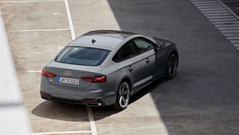  A grey Audi vehicle parked diagonally in an empty outdoor car park, viewed from above