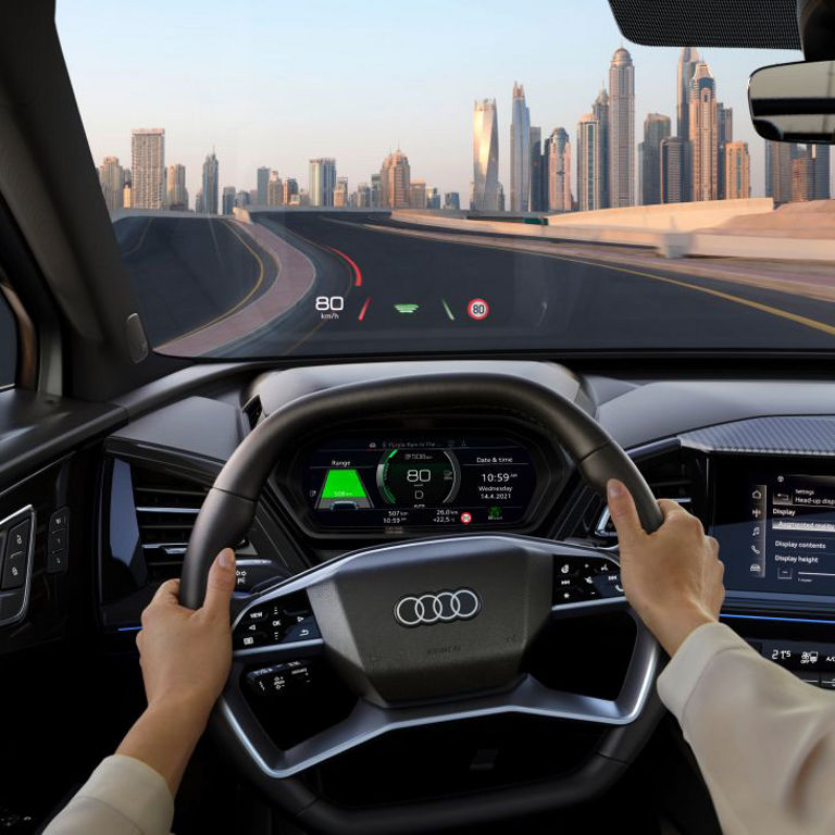 Driver's view inside an Audi vehicle with hands on the steering wheel and digital displays