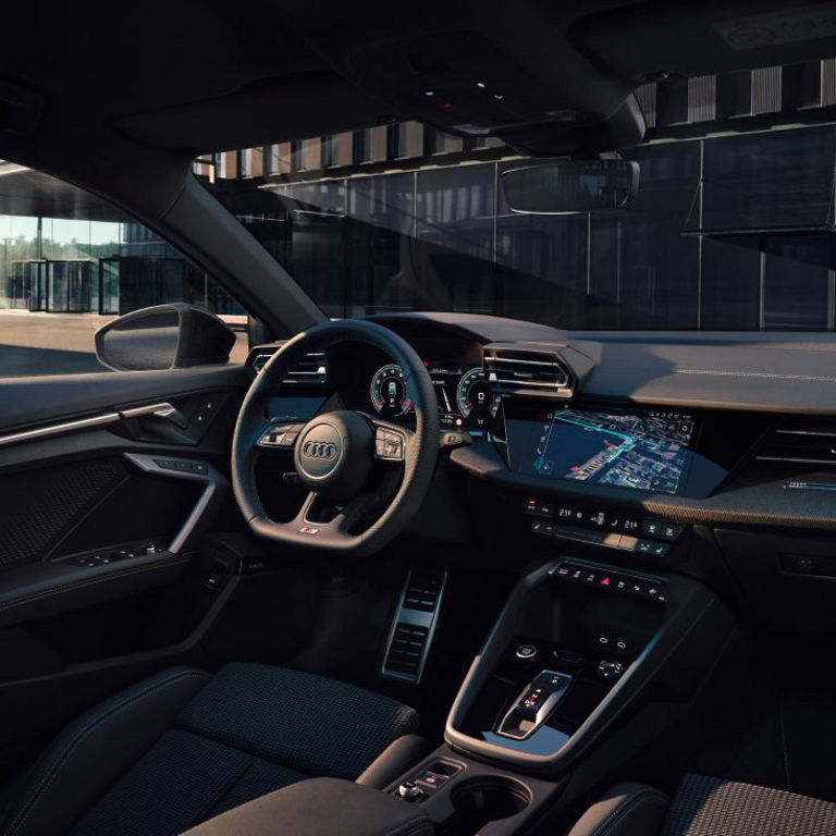 Interior view of an Audi vehicle with steering wheel, dashboard, and touchscreen display