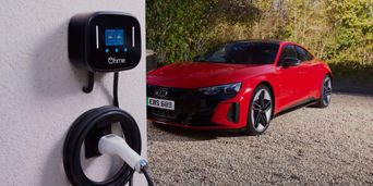 An Ohme charge point on a wall with a parked red Audi electric vehicle in the background 