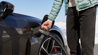 A hand placing a charger plug in to the charge socket on a parked Audi electric vehicle