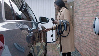 A young woman placing a charger cable in to her Audi electric vehicle