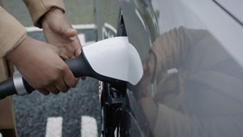 Hands holding and placing a charger cable into the socket of an Audi electric vehicle