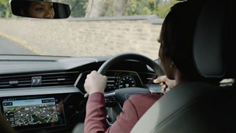 A woman driving an Audi electric vehicle, focal point behind her left shoulder