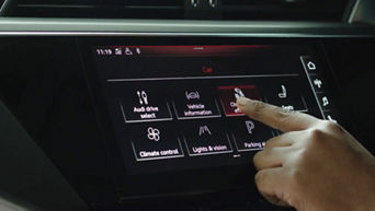 A hand interacting with the digital display on an Audi electric vehicle pressing on charging efficiency