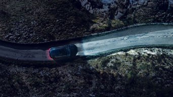 An Audi vehicle (top down view) driving on a road at night, headlights illuminating the road ahead