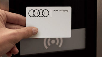 A hand holding an Audi Charging card up to an Audi charge point terminal