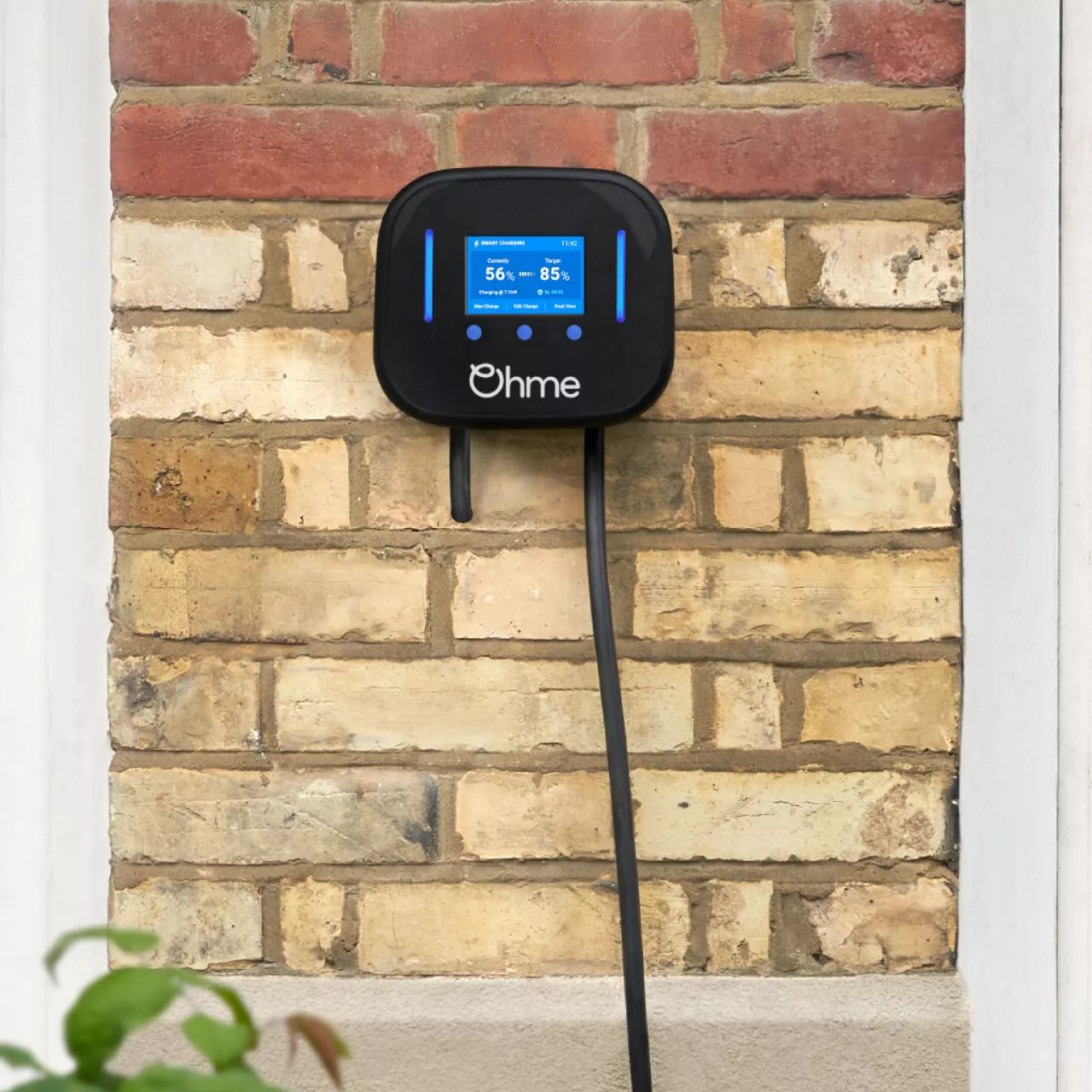 An Ohme electric vehicle home charger mounted to a house wall