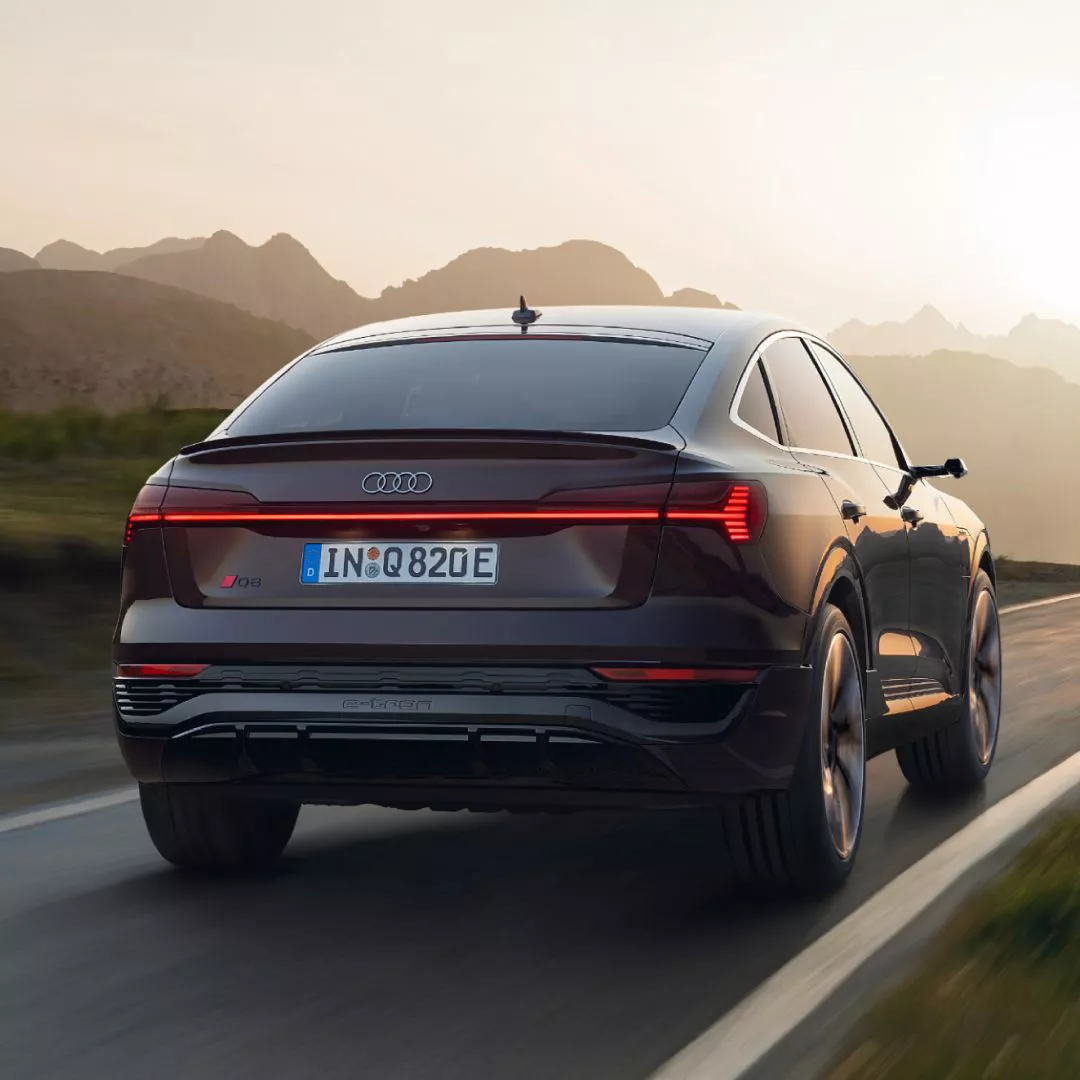 The rear view of an Audi Q8 e-tron driving on a road away from us