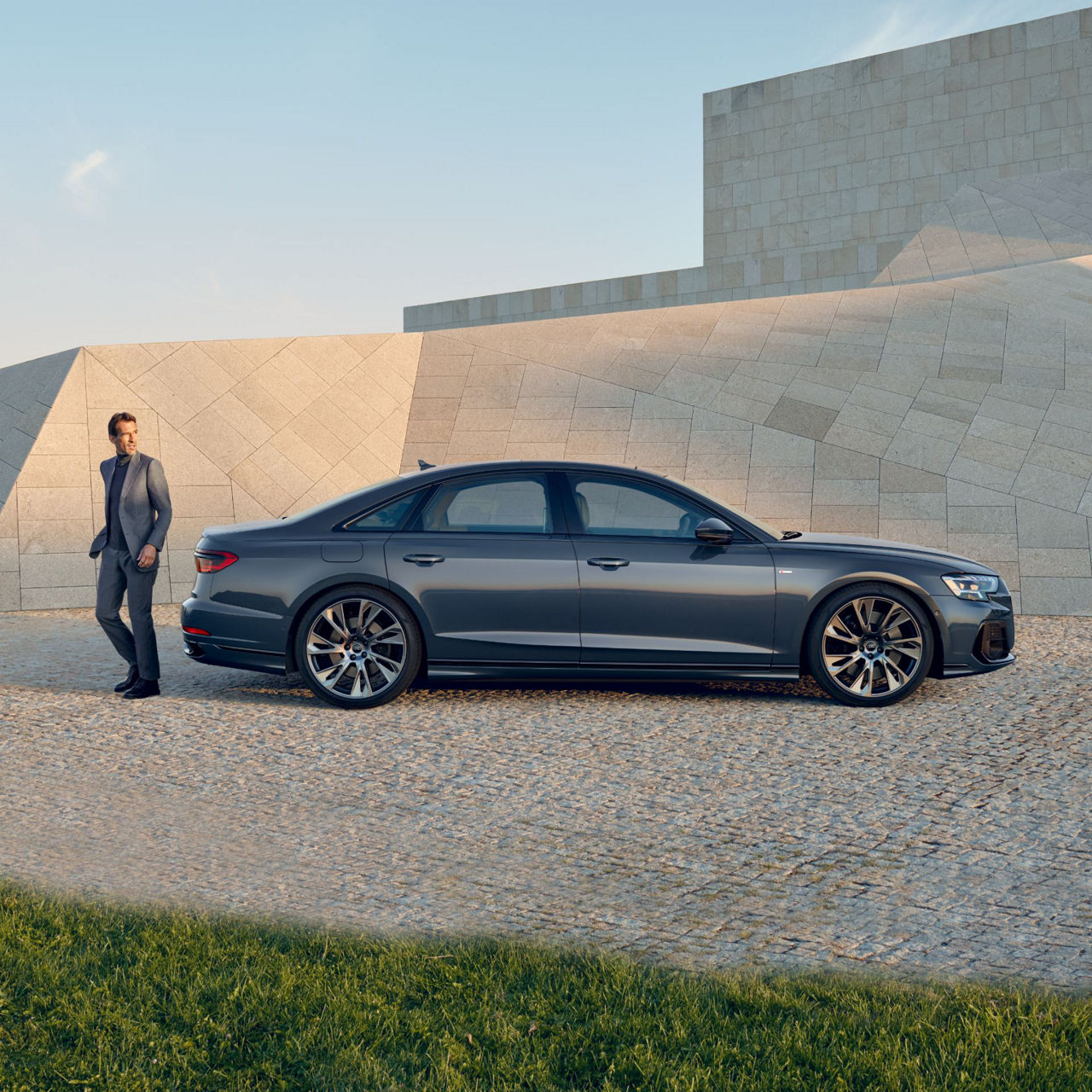 A man walking away from the left a parked Audi vehicle