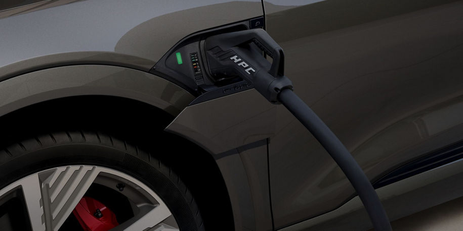 An Audi electric vehicle charging with the focal point on the charger in the charge port