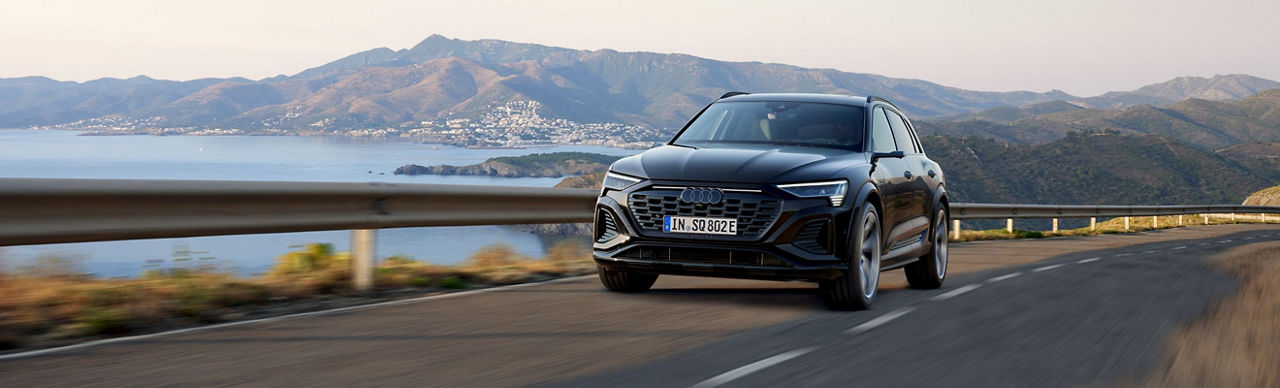  An Audi electric vehicle driving on a road surrounded by mountains in the distance