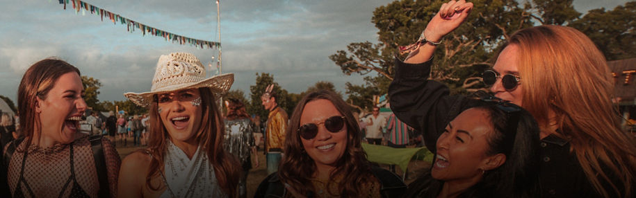 Group of people at an outdoor festival with a sunset background.