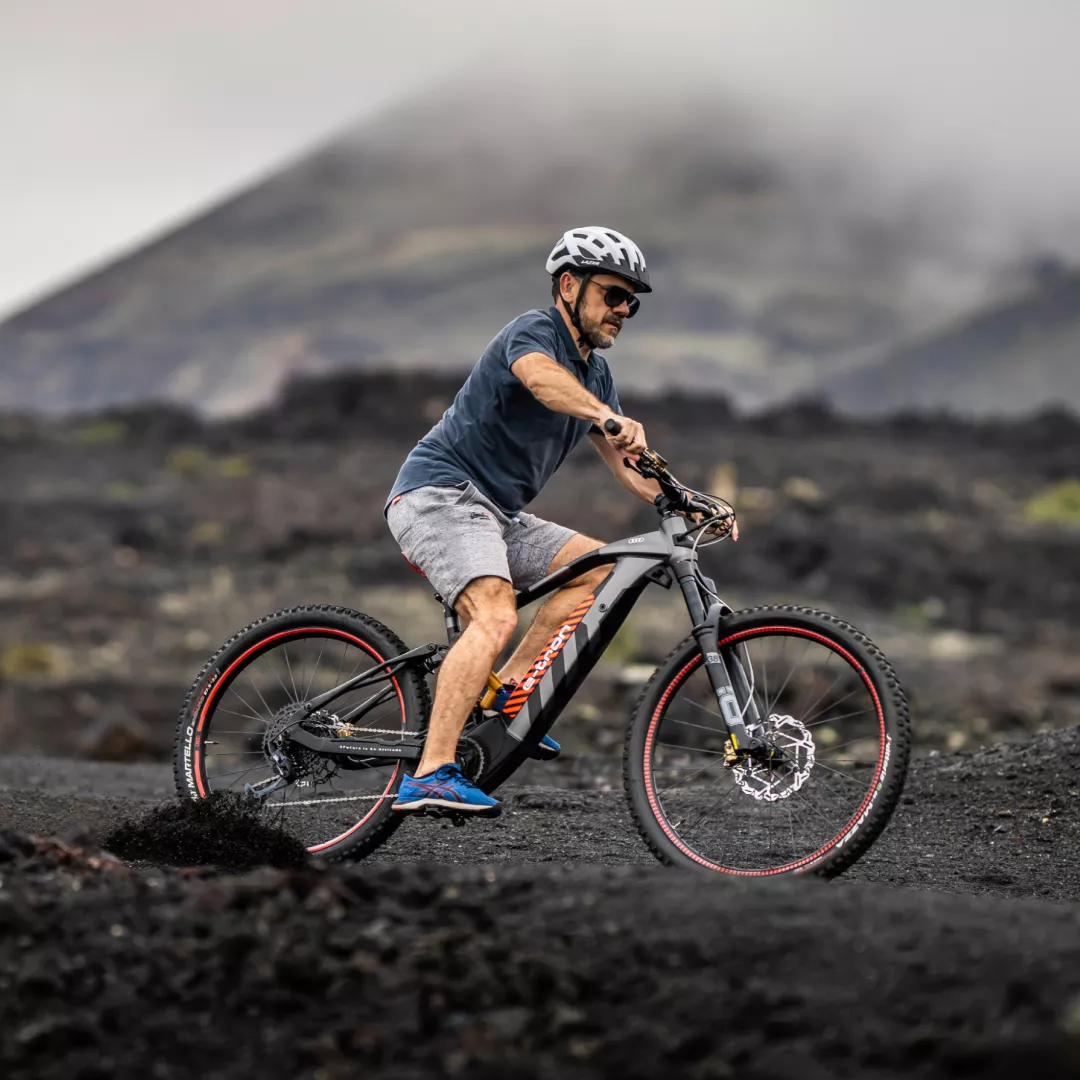 A male cyclist on an Audi electric mountain bike on a muddy and hilly landscape