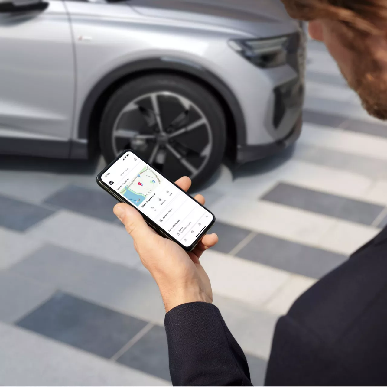 A person looking at the phone in their hand which is displaying the myAudi app