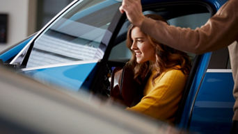 A young woman sitting in an Audi vehicle in an Audi showroom