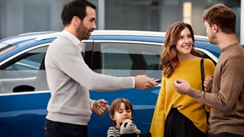 An Audi specialist with a young family who is handing an Audi key fob to them