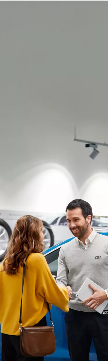 An Audi specialist at an Audi Centre smiling and shaking hands with a female customer