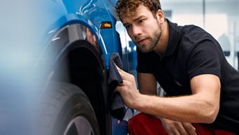 A man with a cloth wiping one of the wheel wings of an Audi electric vehicle