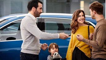 An Audi specialist with a young family who is handing an Audi key fob to them