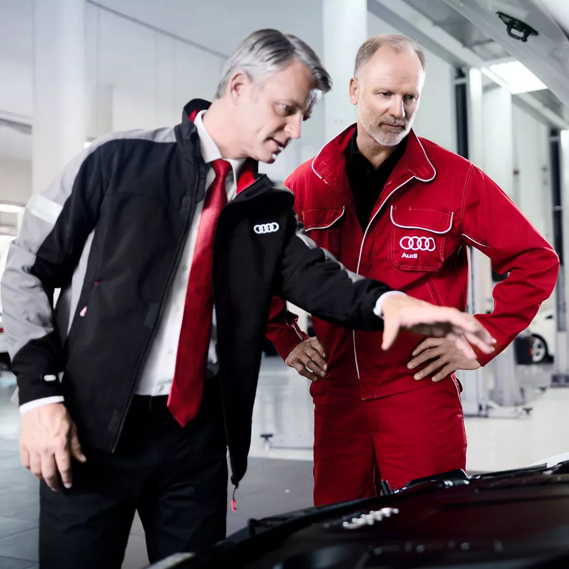 Two male Audi technicians inspecting an Audi vehicle