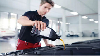 An Audi mechanic pouring oil into the oil tank of an Audi vehicle