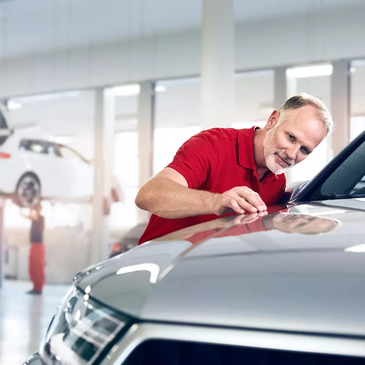 An Audi mechanic inspecting the front of an Audi vehicle