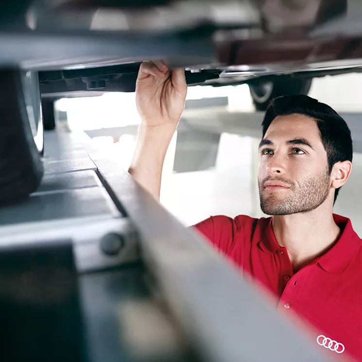 An Audi mechanic inspecting the underside of an Audi vehicle