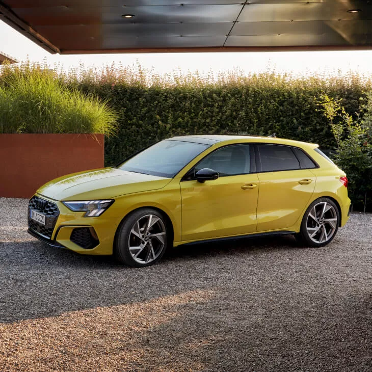 A yellow parked Audi vehicle at a modern home on the drive set in the early evening