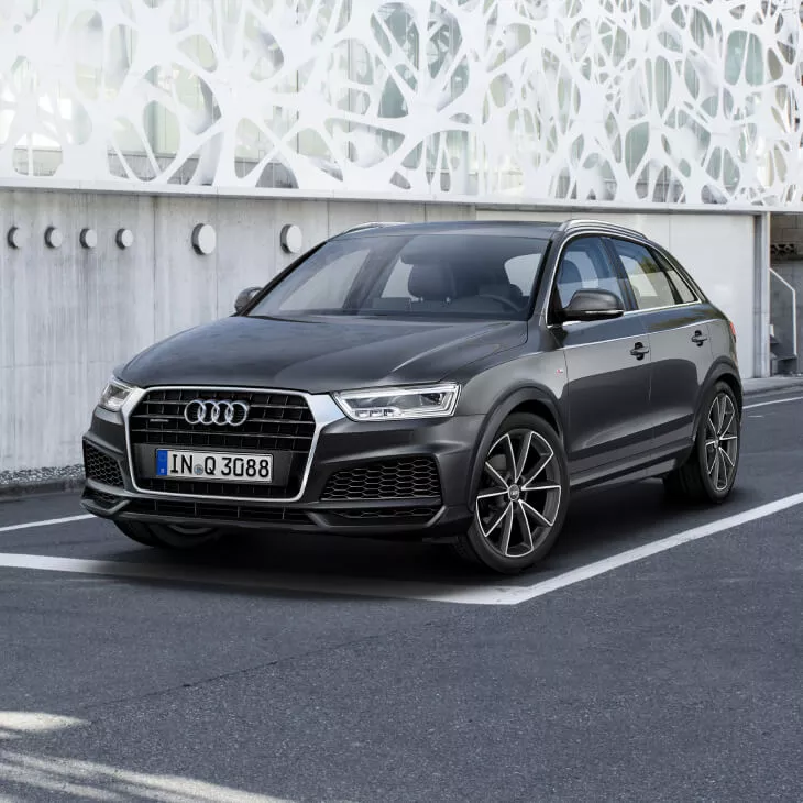 A dark grey Audi Vehicle parked in a parking space in an urban setting in the daytime