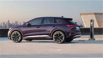 Electric SUV charging at a station with city skyline in the background.