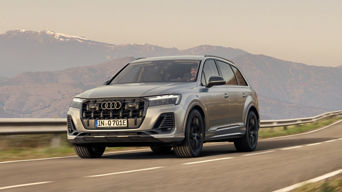 An Audi SUV driving on a road with mountains in the background.