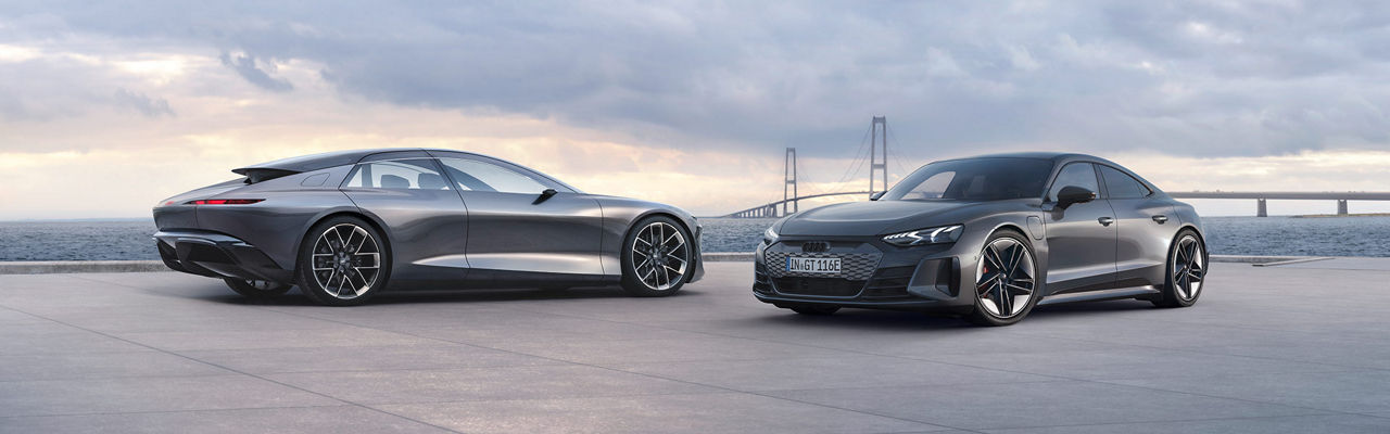  Two Audi vehicles parked facing each other, a body of water and a road bridge in the distance