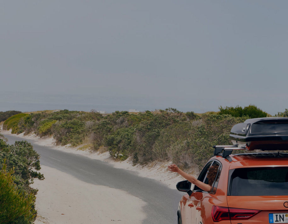 A beach area, sea in the distance and sandy green road edges of a road