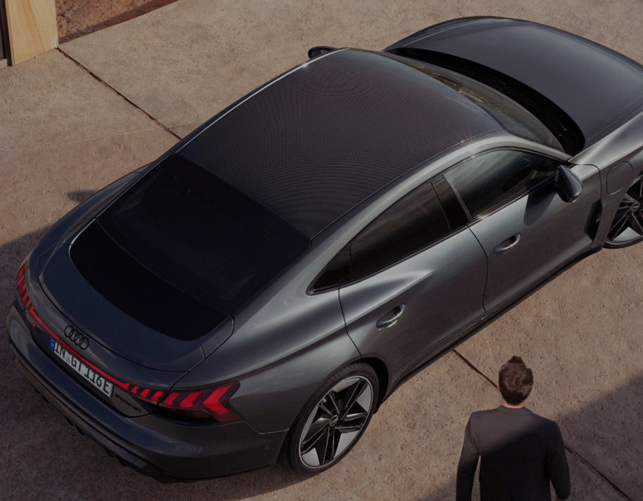 A parked Audi vehicle in an urban setting on a sunny day with a man nearby