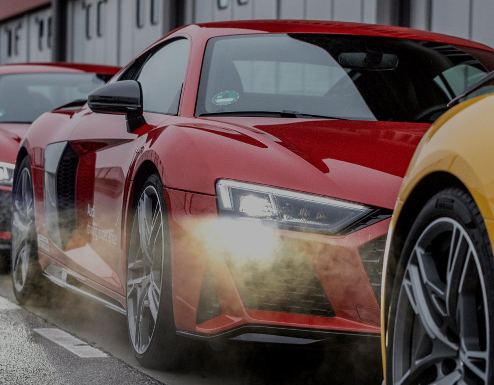 A series of vehicles on a road, a red Audi the focal point with the front right side visible to us