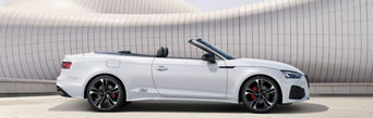 A white Audi vehicle parked in an urban setting on a sunny day