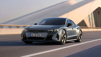 A grey Audi electric vehicle driving on a road, showcasing motion and modern design