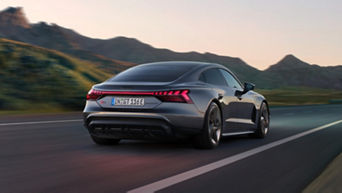 A grey Audi electric vehicle on a highway with a blurred natural landscape in the background