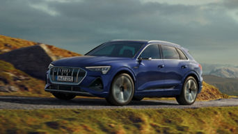 A blue Audi e-tron vehicle driving on a mountainous road