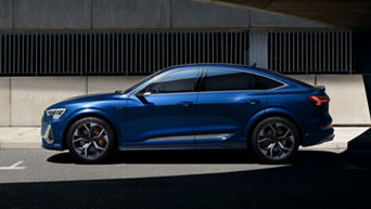 A blue Audi vehicle parked on a street with a modern building in the background