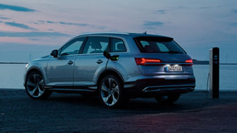 An electric Audi vehicle charging at a dockside station at dusk